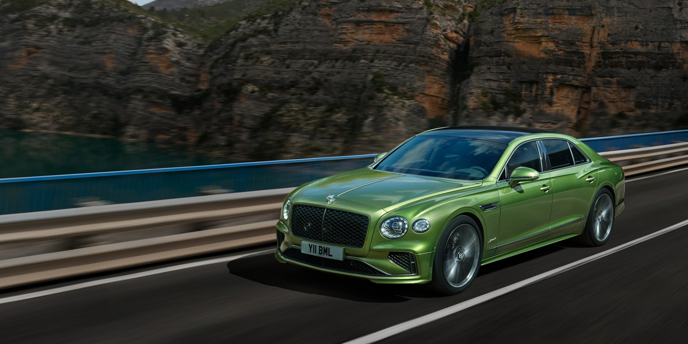 Bentley Antwerp Bentley New Flying Spur Speed v8 hybrid sedan driving dynamically on a mountain road in Tourmaline Green paint