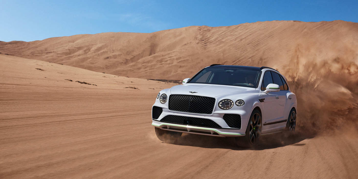 Bentley Antwerp Bentley Bentayga Speed SUV front three quarter in Snow Quarts Pearlescent by Mulliner white paint driving dynamically through the desert