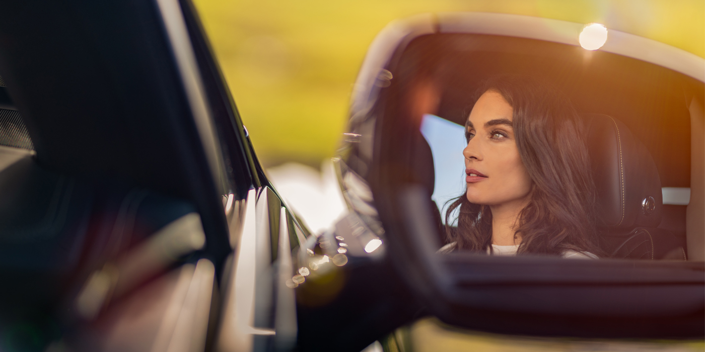 Bentley Antwerp profile of dark haired woman's face in mirror of Bentley car in sunlight