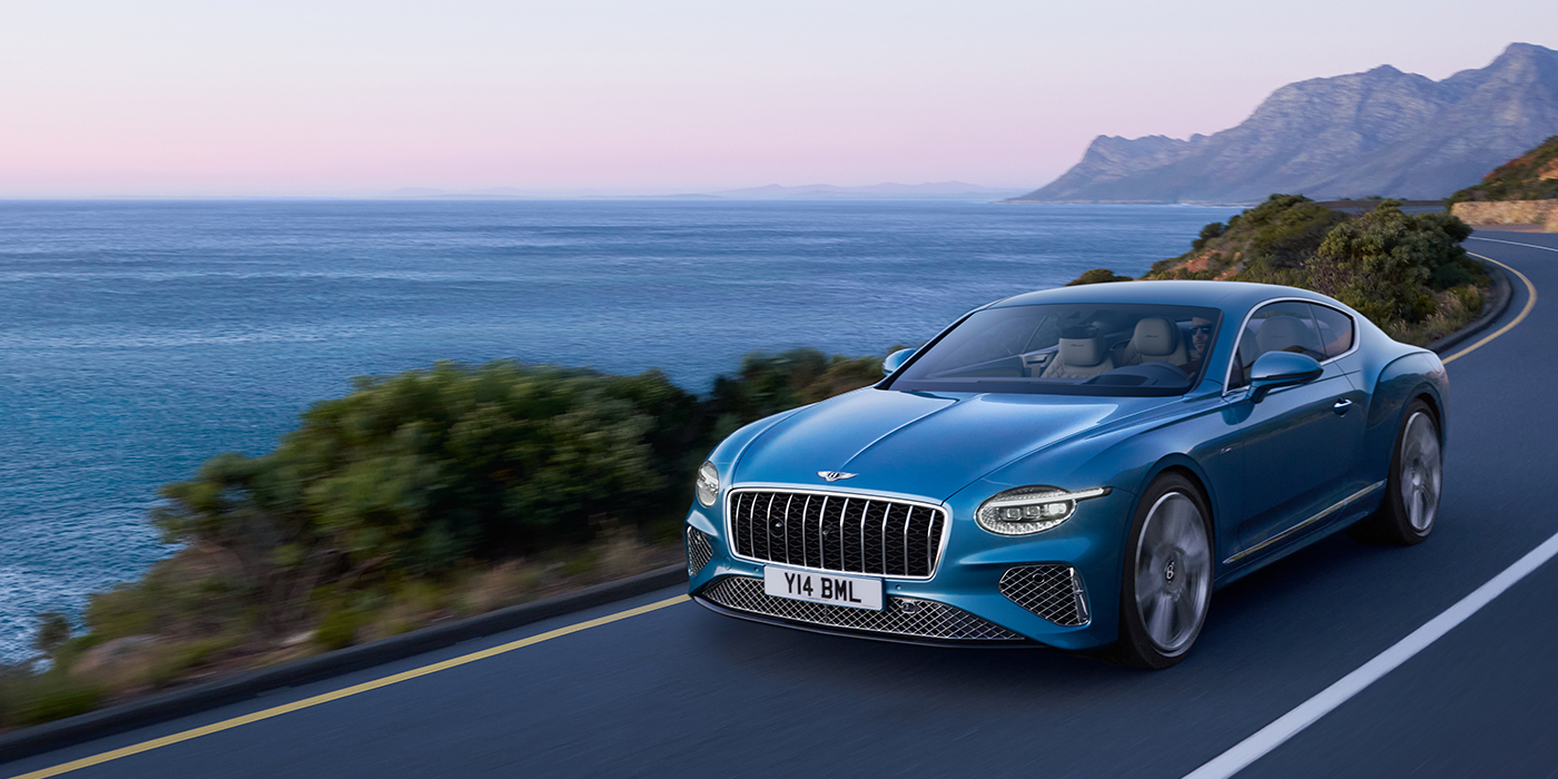 Bentley Antwerp New Bentley Continental GT Azure coupe in Light Windsor blue paint with 22 inch Azure wheels and chrome grill, driving dynamically by the sea