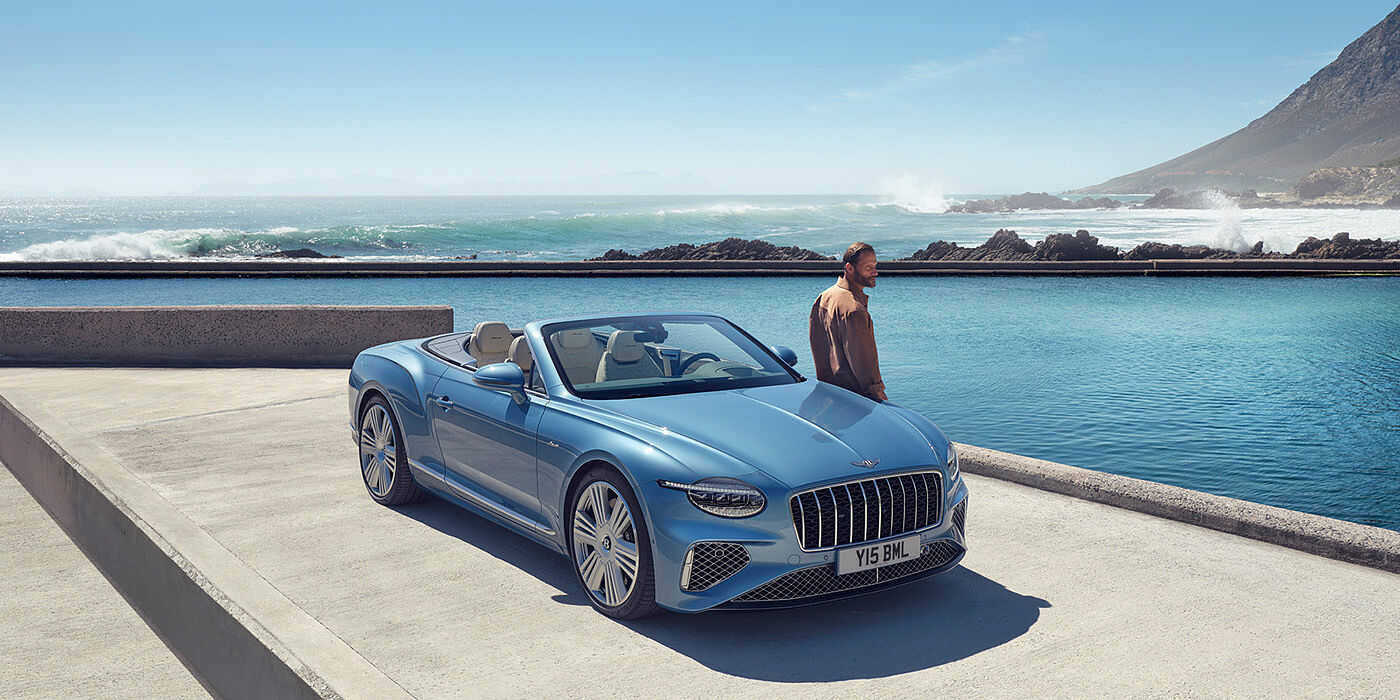 Bentley Antwerp New Bentley Continental GTC Azure convertible front view in Light Windsor blue paint with 22 inch ten spoke wheels parked by the sea in the sunshine