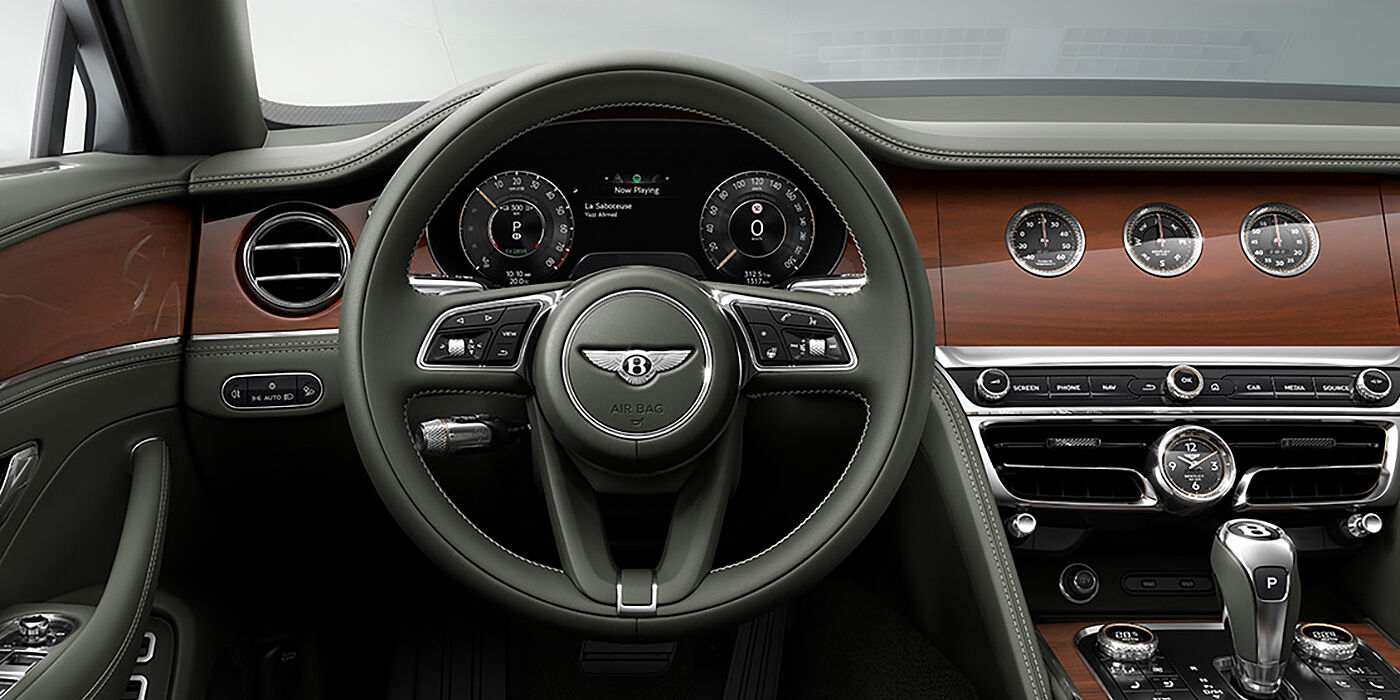 Bentley Antwerp New Bentley Flying Spur sedan front cabin in Cumbrian Green hide and Crown Cut walnut veneer showing steering wheel and Rotating Display with three clocks on face