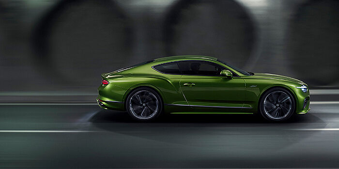  Bentley Antwerp Bentley Continental GT coupe in Tourmaline Green paint driving in profile on a dark road