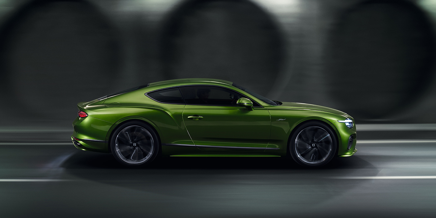 Bentley Antwerp Bentley Continental GT coupe in Tourmaline Green paint driving in profile on a dark road